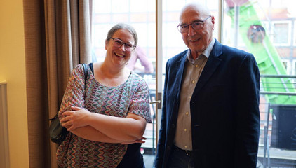 Dr. Saskia Otte (l.) aus dem Amalie Sieveking Krankenhaus blickt mit einem anderen Gast lächelnd in die Kamera beim Einführungssymposium „Die Zukunft ist alt!“ von Priv.-Doz. Dr. Gödel, Chefarzt der Klinik für Geriatrie im Albertinen Zentrum für Altersmedizin im Albertinen Krankenhaus in Hamburg.