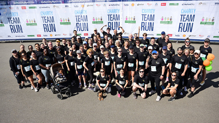 Gruppenfoto der Mitarbeitenden der Immanuel Albertinen Diakonie beim HafenCityRun 2026 in Hamburg. Das Charity-Team posiert vor dem Veranstaltungsbanner nach dem Firmenlauf für den guten Zweck in der HafenCity.