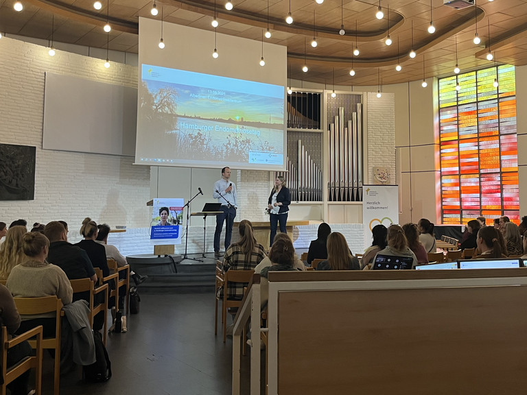 Blick über die Sitzreihen zur Bühne mit Leinwand in der Kirche am Krankenhaus beim zweiten Hamburger Endometriosetag 2025 der Klinik für Gynäkologie und Geburtshilfe im Albertinen Krankenhaus