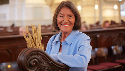 Eine Frau lächelt neben den Kirchenbänken fröhlich in die Kamera beim 10. Herzbrücke-Benefizkonzert im Hamburger „Michel“ der Albertinen-Stiftung.