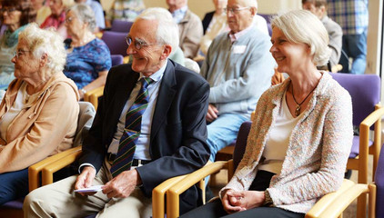 Prof. Dr. Wolfgang von Renteln-Kruse und Studienleiterin Dr. Ulrike Dapp sitzen vorne in den Stuhlreihen im Publikum bei der Jubiläumsveranstaltung mit Symposium und einer Dankesveranstaltung zum 25-jährige Bestehen der LUCAS Langzeit-Kohortenstudie im Hamburger Albertinen Haus und Kirche am Albertinen Krankenhaus..