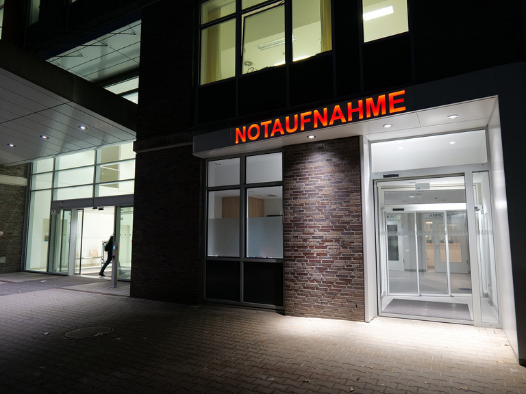 Beleuchteter Eingang der Zentralen Notaufnahme am Albertinen Krankenhaus mit rotem Schriftzug „NOTAUFNAHME“ über den Glastüren.